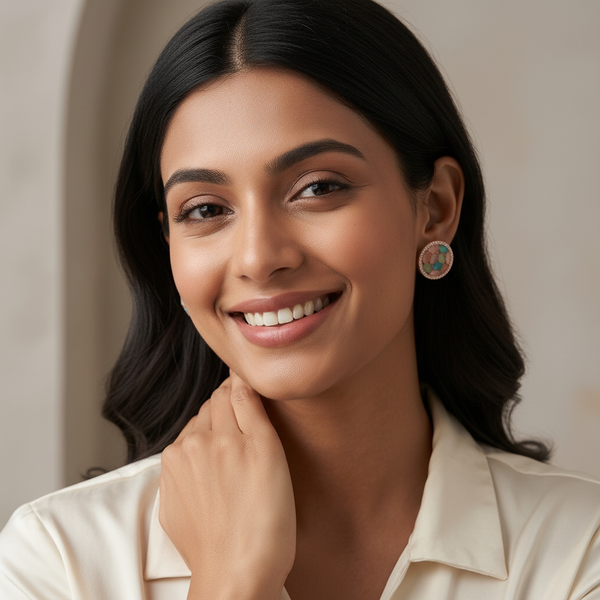 A pair of Diaura Jewels Korean style circular stud earrings featuring multi-color pastel stones on a white marble surface with rose quartz and silk ribbon.